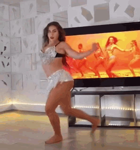 a woman is dancing in front of a television in a living room
