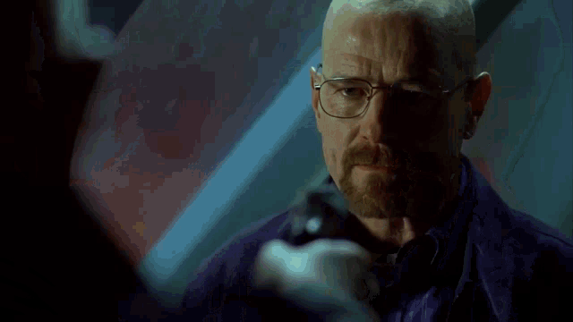 a bald man with glasses and a beard is holding a gun and saying yeah .