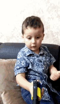a young boy is sitting on a couch playing with a toy