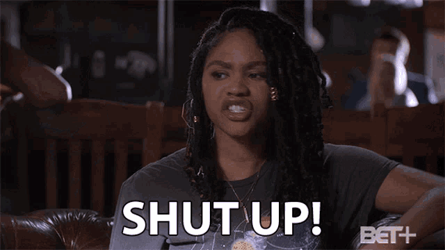 a woman sitting on a couch with the words shut up on her face