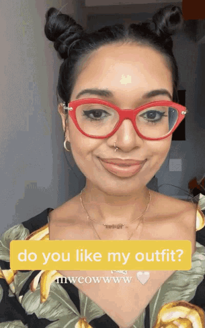 a woman wearing red glasses and a floral shirt is asking if she likes her outfit