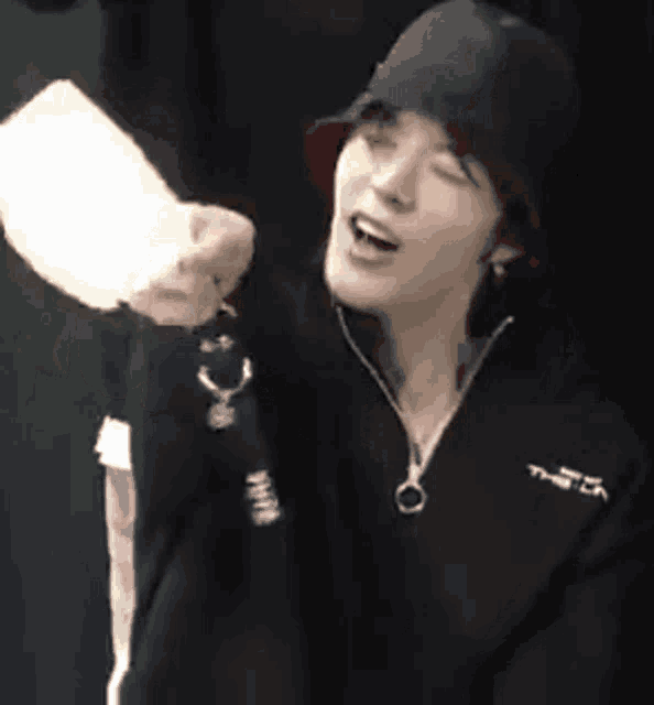 a man wearing a hat and a black jacket is holding a piece of paper .