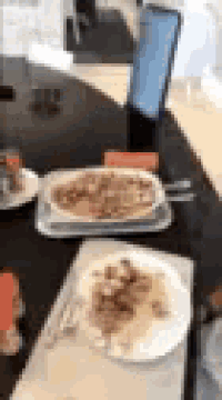 a blurred image of a table with plates of food and a laptop on it .