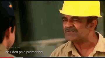 a man wearing a hard hat talks to another man