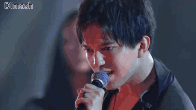 a crowd of people watching a wave on a stage with the name dimash on the bottom