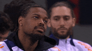 a man with dreadlocks and a beard is sitting next to another man with a beard
