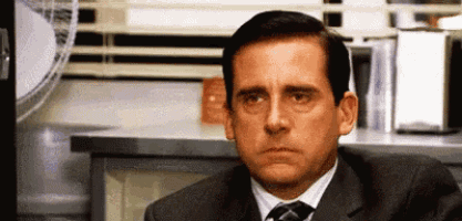 a man in a suit and tie is sitting in front of a television in an office .