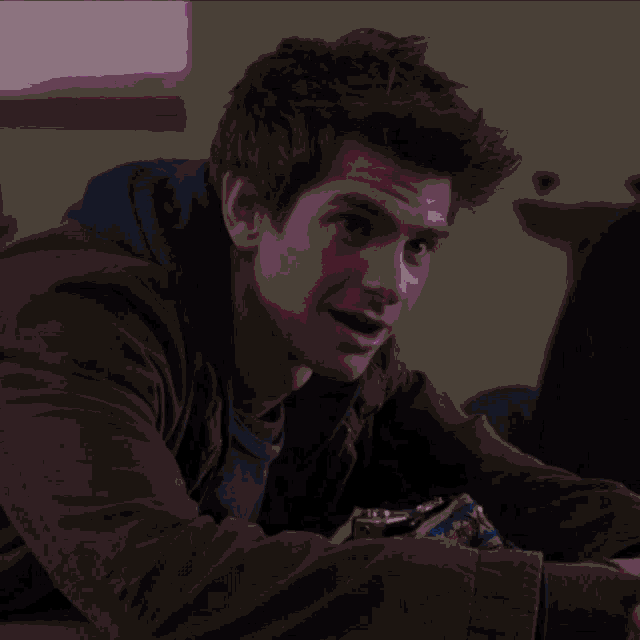 a young man in a green jacket is sitting at a table