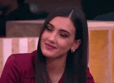 a woman in a red shirt and hoop earrings is smiling .