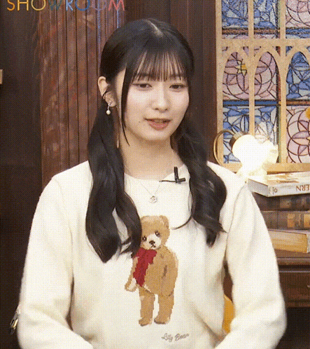 a girl wearing a sweater with a teddy bear on it and the word silly bear on it
