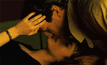 a man and a woman are kissing and the woman is touching the man 's ear .
