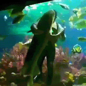 a man in a black suit is standing in front of a large fish tank
