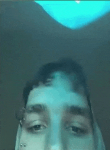 a close up of a man 's face with a blue light in the background .