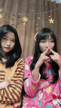 two girls are sitting next to each other and one is covering her nose with her hand