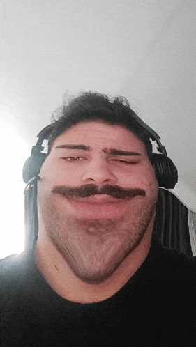 a man with a beard and mustache is wearing headphones and making a funny face