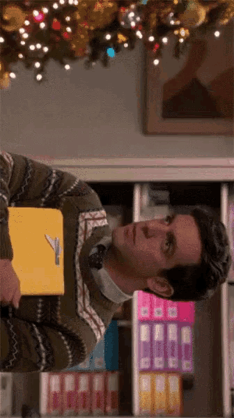 a man in a sweater holds a yellow folder with a key on it
