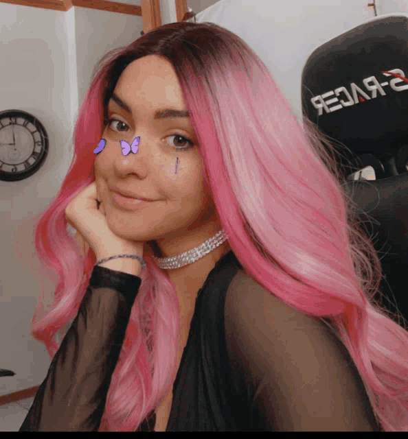 a woman with pink hair is sitting in front of a black chair that says redarc on it