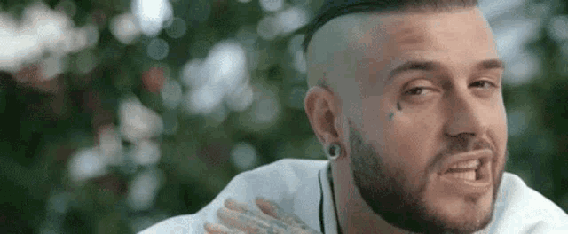 a man with a beard and piercings is making a funny face while looking at the camera .