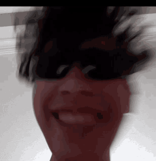 a blurry picture of a person wearing sunglasses making a funny face .