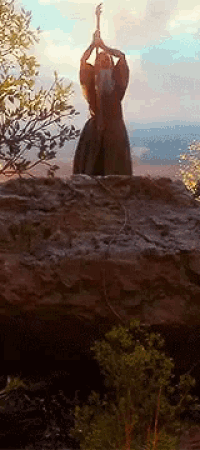 a man is standing on a rock holding a sword in his hands