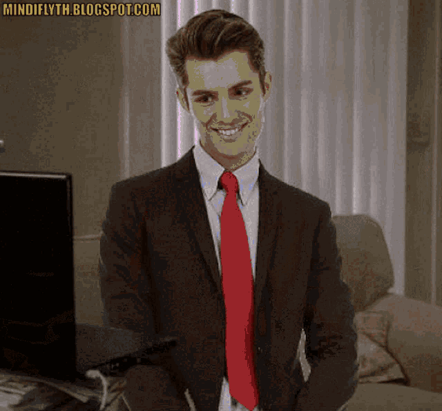 a man in a suit and red tie is smiling in front of a laptop with the website mindifyth.blogspot.com written above him