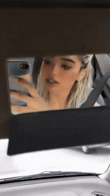 a woman is taking a picture of herself in the rear view mirror