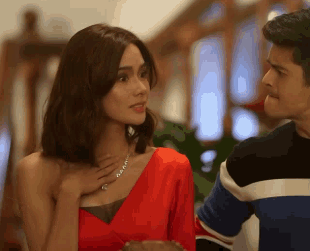 a man and a woman are looking at each other and the woman is wearing a red dress