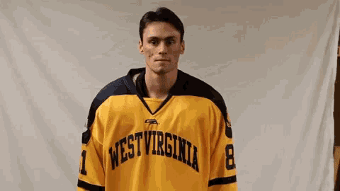 a man in a yellow east virginia jersey gives a thumbs up