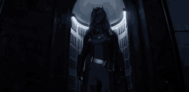 a woman in a red and black costume is standing in a doorway