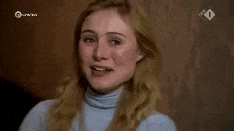 a woman in a blue sweater is covering her face with her hand .