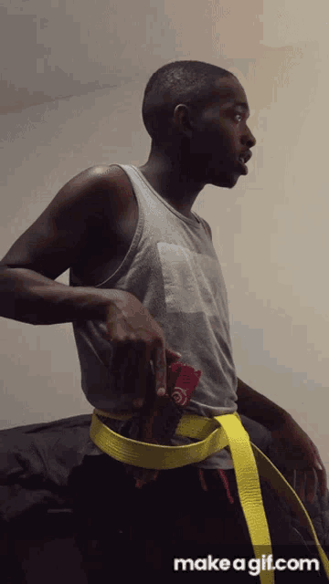 a man is wearing a yellow belt with make a gif.com on the bottom right