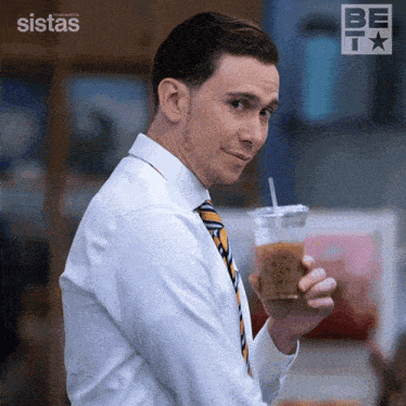 a man in a white shirt and tie holds a cup of coffee with a straw