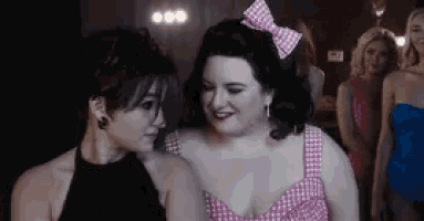 a woman with a pink bow in her hair looks at another woman