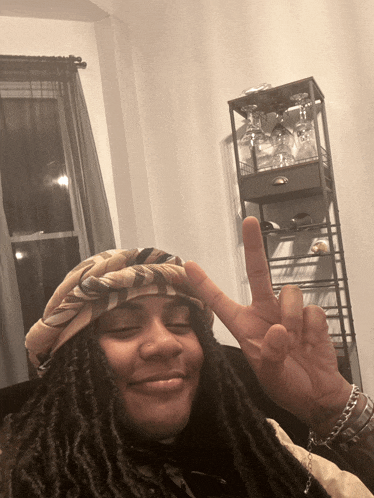 a woman wearing a head scarf giving the peace sign