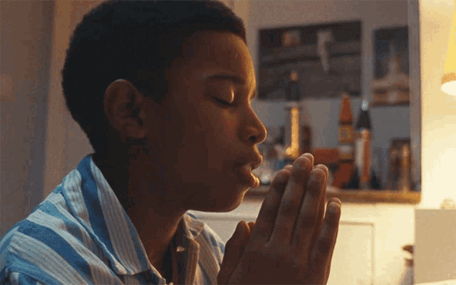 a young boy praying with his eyes closed and his hands folded