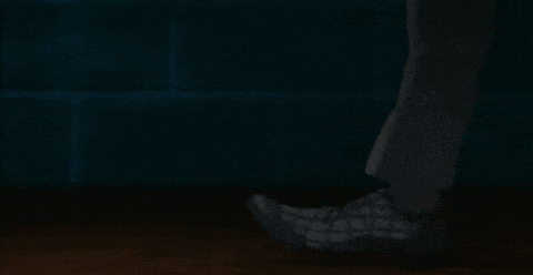 a person 's feet are shown in a dark room with a couch in the background