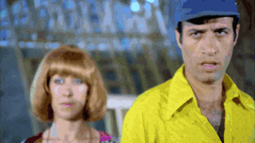 a man in a yellow shirt is standing next to a woman in a pink dress