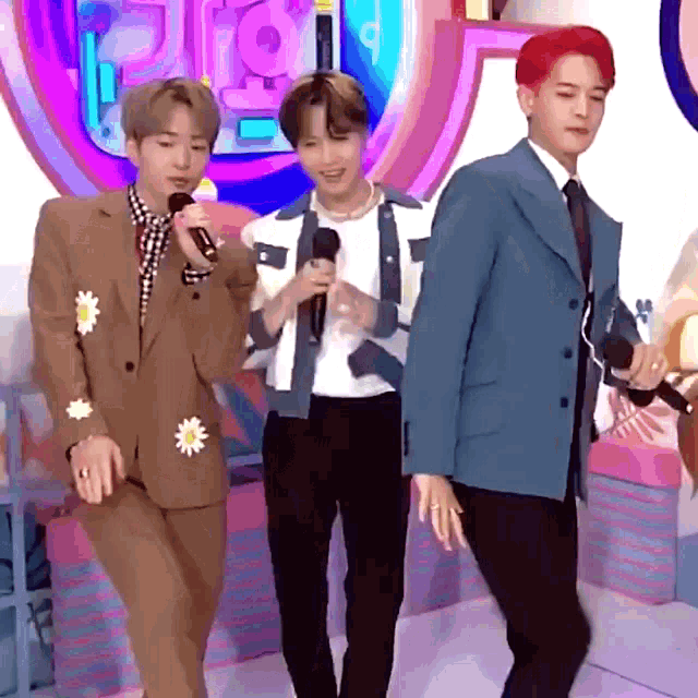 a man with red hair is holding a microphone while standing next to two other men in suits