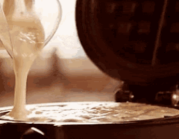 a person is pouring liquid into a waffle maker .
