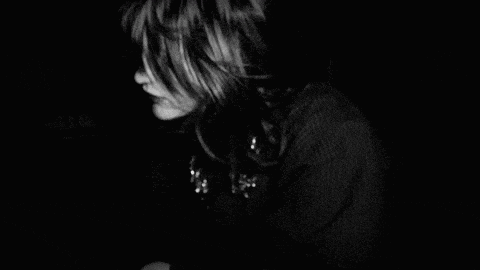 a black and white photo of a woman praying in a dark room .