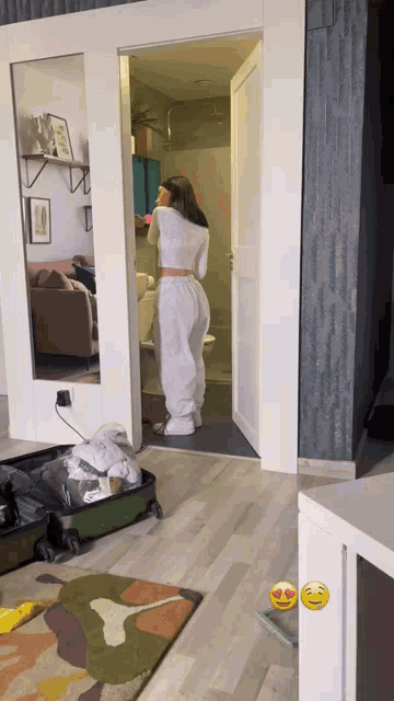 a woman is standing in a room with a suitcase and a couch