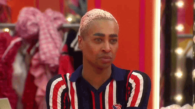 a man wearing a red white and blue striped shirt is looking at himself in the mirror .