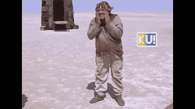 a man is standing in the middle of a snowy field with a ku sticker on his shoulder