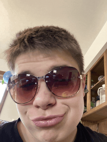 a young man wearing sunglasses is making a face