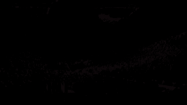 a crowd of people are gathered in a stadium with lights shining on them
