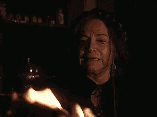 a woman is holding a candle in her hand and looking at it