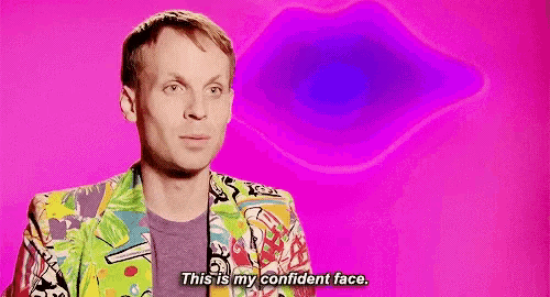 a man in a colorful jacket is standing in front of a pink background and saying `` this is my confident face . ''