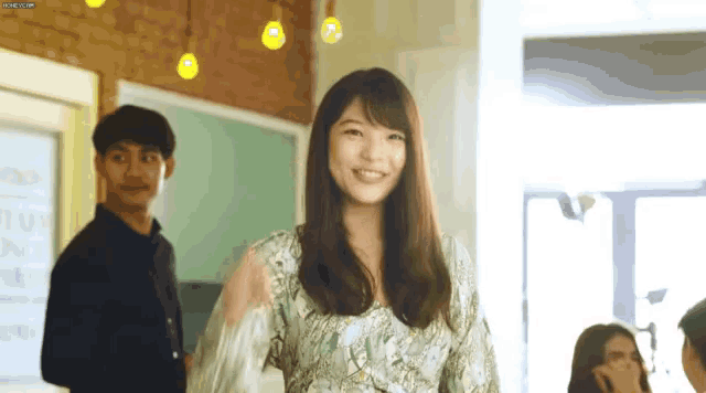 a woman in a floral dress stands in front of a group of people