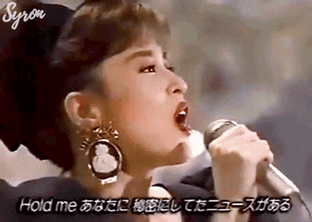 a close up of a woman singing into a microphone with foreign writing