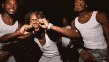 a group of young men in white tank tops are dancing together